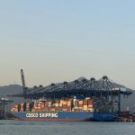 COSCO Shipping cargo ship loaded with containers at a busy port.